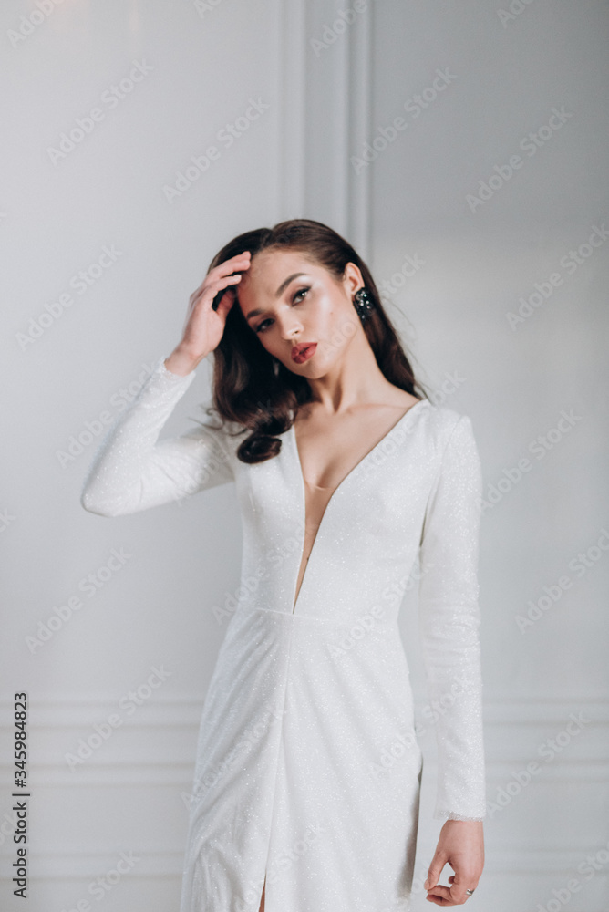 a beautiful bride in a white glittering wedding dress with brown hair poses in a photo Studio a beautiful bride in a white glittering wedding dress with brown hair poses in a photo Studio