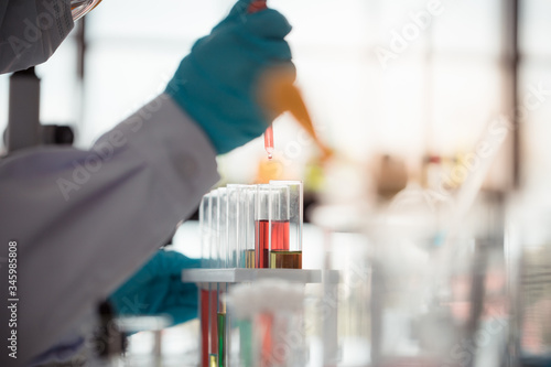 Scientist hold pipette adding fluid to test tubes or glassware with copy space using as background science, medical , education, biology, chemistry concept.
