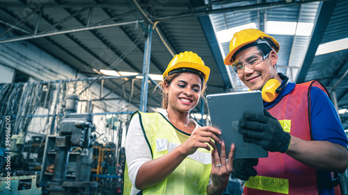 Two multiethnic industrial workers looking at tablet in the warehouse.