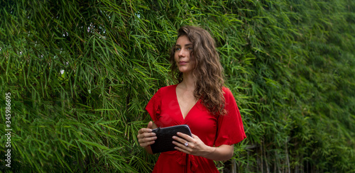 Outdoor, fashion portrait of an elegant, fashionable woman wearing a dress. Fashion concept with natural exotic background for a banner for social media. Advertising. Snake python accessory.