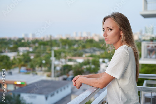 Single female standing outside on residential balcony sunset isolation