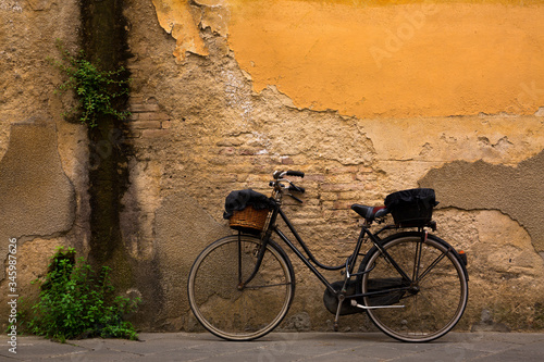 Old, vintage bicycle against a weathered, textured wall in Lucca, Italy