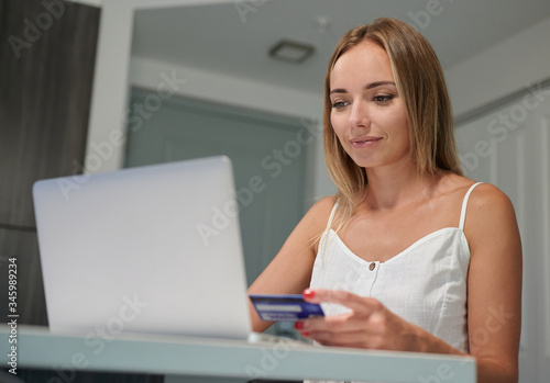 Happy female with laptop online shopping credit card in one hand