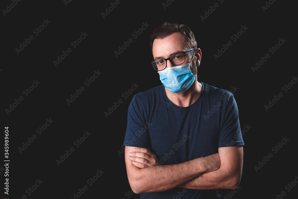 Adult person with protective face mask posing on a black background - social issues with virus and contagious safety measures. Adult person with protective face mask posing on a black background - social issues with virus and contagious safety measures.