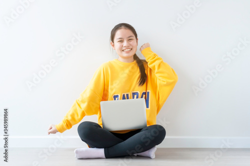 New normal life, Asian female teenager use 18 years old do online learning from home by laptop, woman wearing casual yellow cloth use laptop for work from home during corona virus crisis. Thailand.