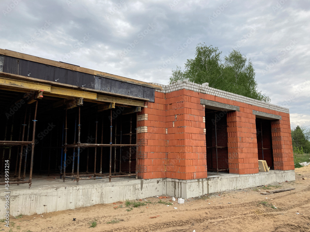 Close up of unfinished house in residential area. Modern architecture of construction brick house for comfortable stay of people.