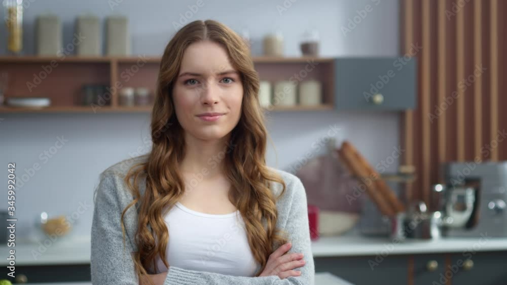 Attractive woman looking camera in kitchen. Focused girl crossing hands indoors. Attractive woman looking camera in kitchen. Focused girl crossing hands indoors.