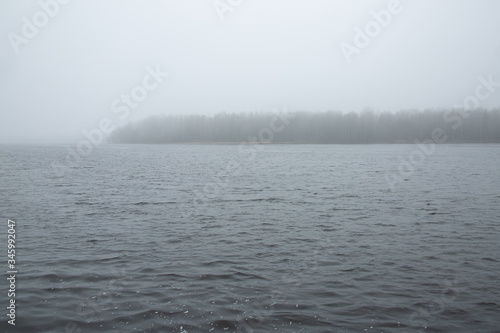 Cold foggy morning over the northern lake with forest island