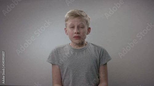 Blonde caucasian kid is showing the importance of sneezing into an elbow in order to prevent the spread of Covid19 infection