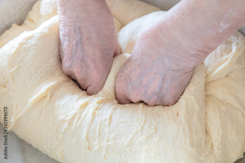 Kneading the dough in home. Hands of an elderly woman knead the dough in her home. 