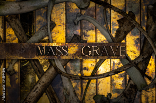 Photo of real authentic typeset letters with selective focus on Mass Grave text over skeletal bones on vintage textured grunge copper and gold background