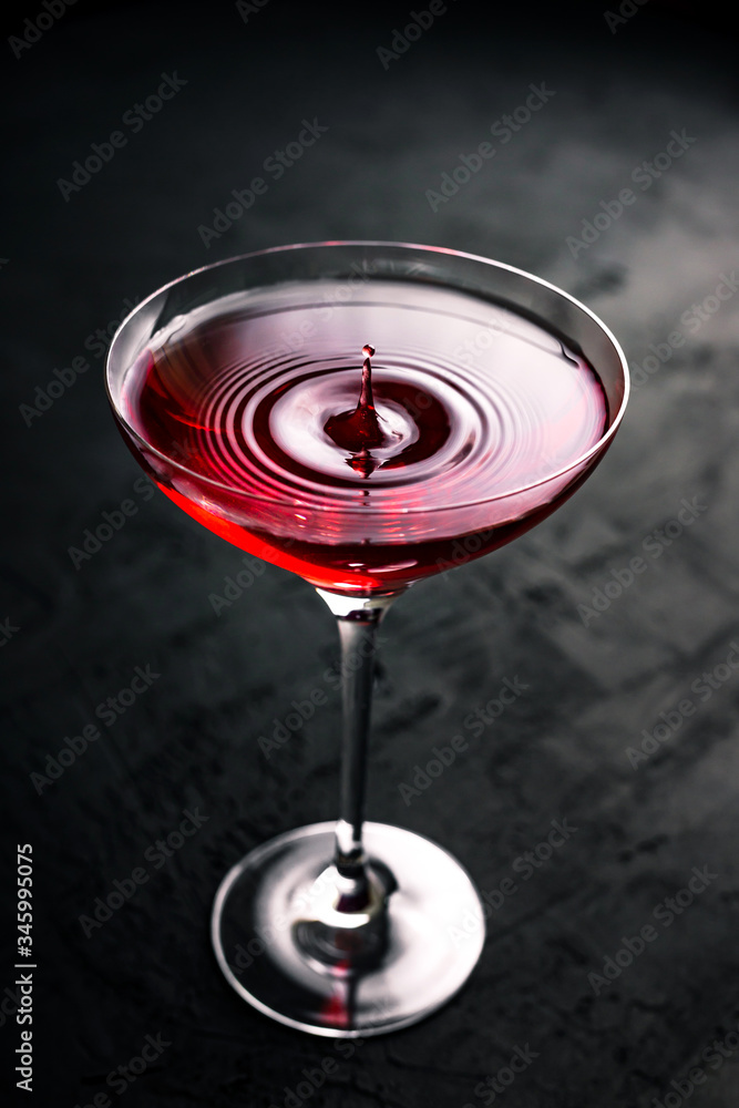 A drop falling into a beautiful cocktail glass with cosmopolitan
