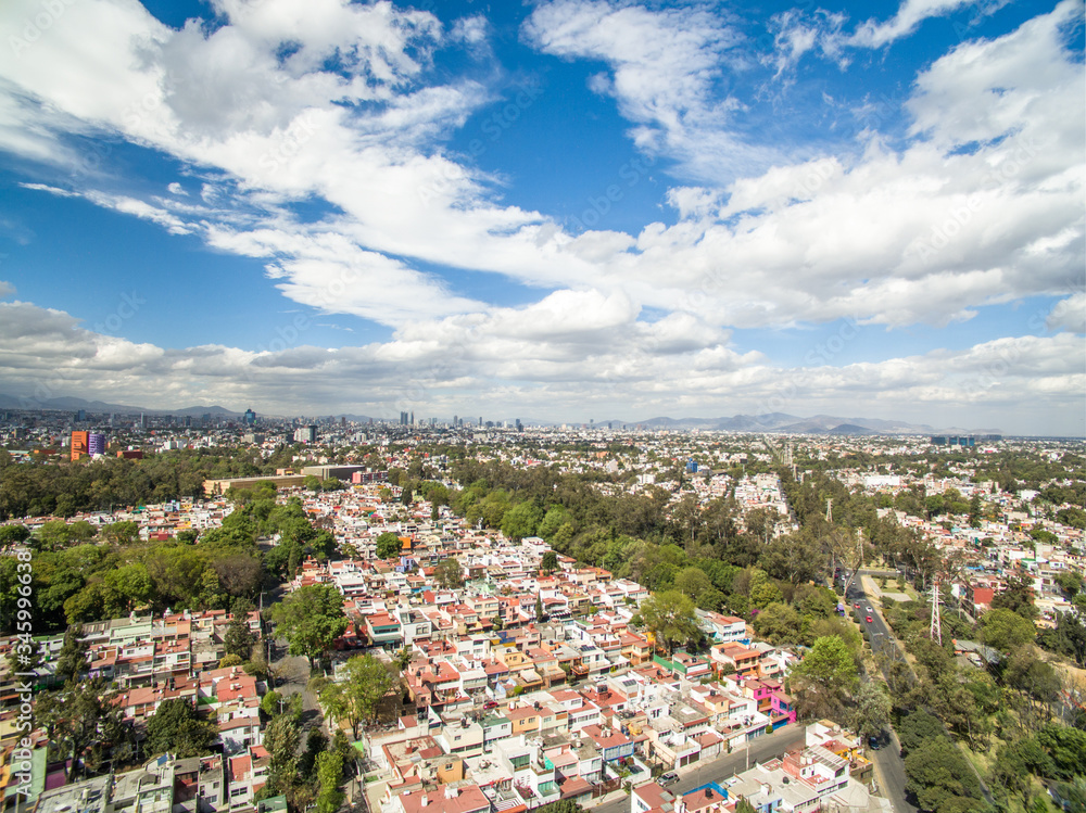 Vista aérea panorámica del sur de la Ciudad de México con un cielo nublado como fondo.
