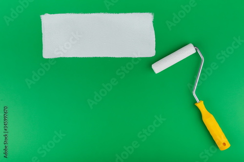 mock up of srip of white paint and painting roller on green background photo