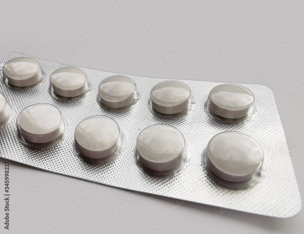 White pills in pack on light gray background. Disease treatment. The fight against coronavirus 2020. White pills in pack on light gray background. Disease treatment. The fight against coronavirus 2020.