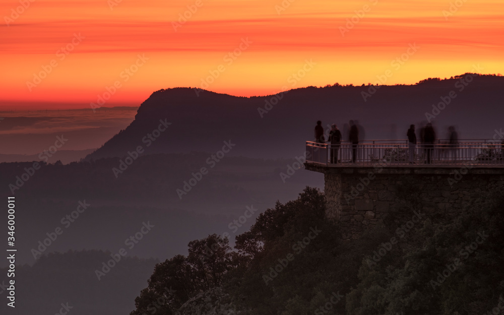 Mirador de alta montaña con gente contemplando la puesta de sol.