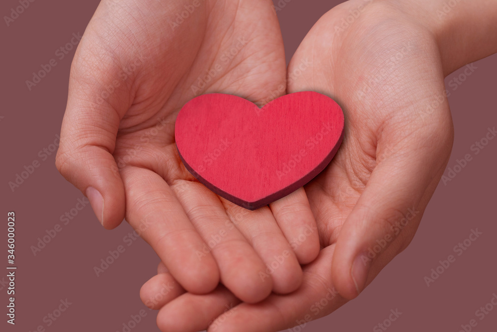 Women's hands hold a red wooden heart in their palms. Space for text. The concept of love, Valentine's day, friendship, cardiology. Women's hands hold a red wooden heart in their palms. Space for text. The concept of love, Valentine's day, friendship, cardiology.
