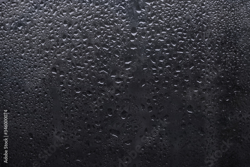 Drops on a dark window pane. Dark background with bokeh. Raindrops, condensation, bad weather.