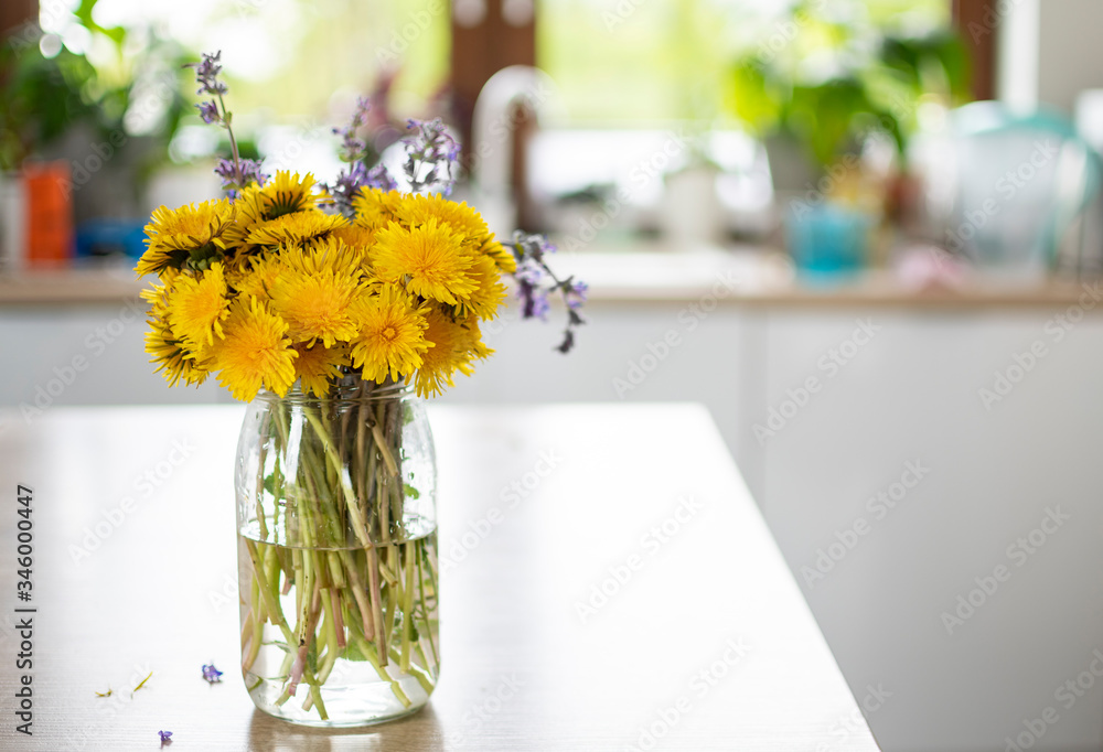 Bukiet żółtych polnych kwiatów stojący w kuchni w dziennym jasnym świetle - obrazy, fototapety, plakaty 
