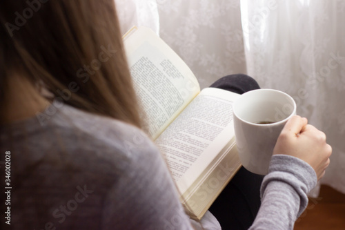 woman reading a book and has a cup of coffee