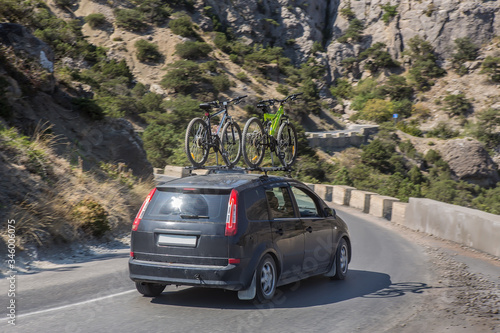 car with bicycles on the upper trunk moves on a road in the mountains © Yuri Bizgaimer