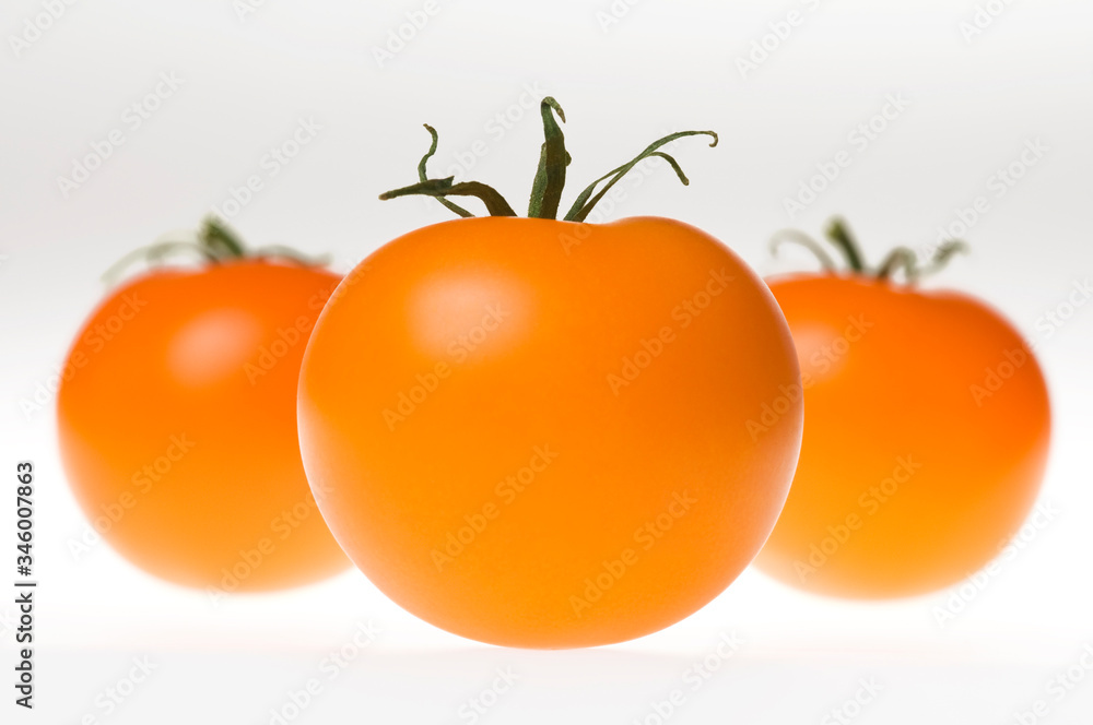 Bunch of fresh ripe orange tomatoes with green stem, isolated on white background. Studio shot Bunch of fresh ripe orange tomatoes with green stem, isolated on white background. Studio shot