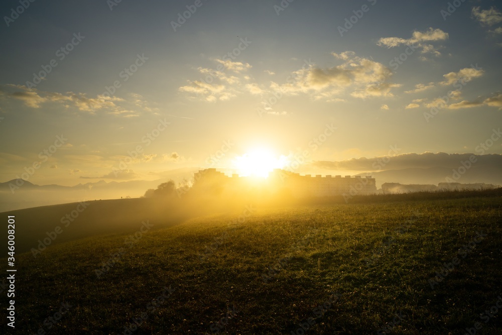 Sunrise and sunset, beautiful clouds over the meadow, hills and buildings in the town. Slovakia Sunrise and sunset, beautiful clouds over the meadow, hills and buildings in the town. Slovakia