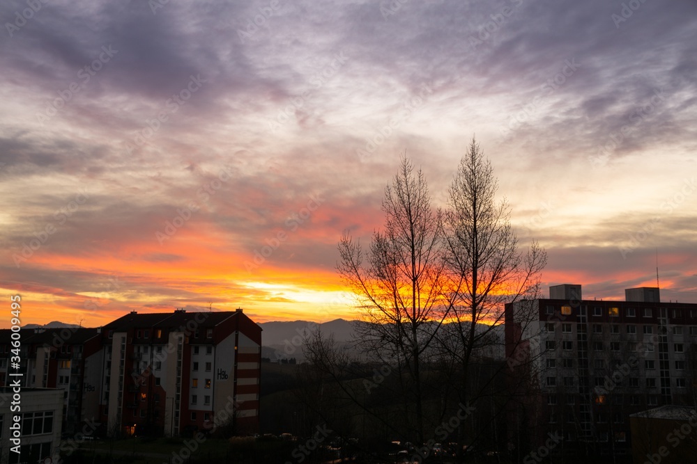 Sunrise and sunset, beautiful clouds over the meadow, hills and buildings in the town. Slovakia