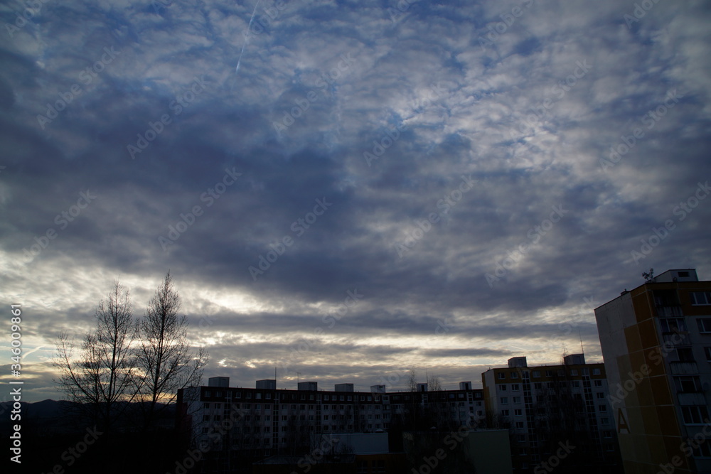 Naklejka premium Sunrise and sunset, beautiful clouds over the meadow, hills and buildings in the town. Slovakia