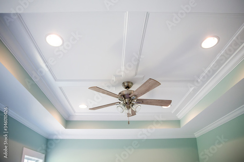 White tray master bedroom ceiling in small new construction house with windows and a ceiling fan and pale blue turquoise walls