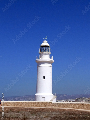 White lighthouse against the blue sea and sky. Summer landscape.