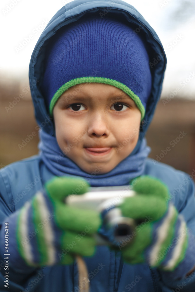 Portrait of the caucasian cute little cheerful child boy hold photo camera. Compact photographer doing taking the picture. Portrait of the caucasian cute little cheerful child boy hold photo camera. Compact photographer doing taking the picture.