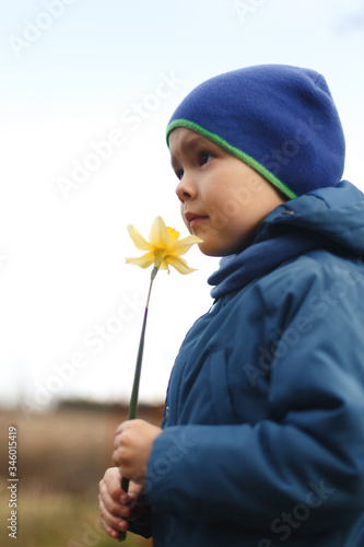 Wallpaper Mural Happy little boy sniffing a flower on a green garden. White background. Torontodigital.ca