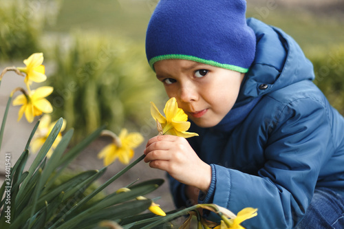 Wallpaper Mural Happy little boy sniffing a flower on a green garden. Torontodigital.ca