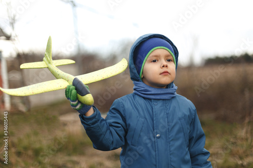 Wallpaper Mural Seriously kid playing with toy airplane against garden background. Torontodigital.ca