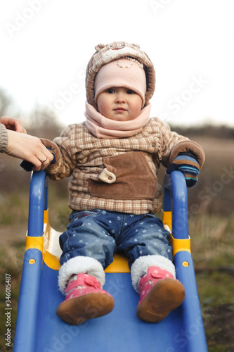 Wallpaper Mural A happy child sits on a children's slide and smiles in a stylish brown jacket and hat in autumn. Fashion and style for children. Torontodigital.ca