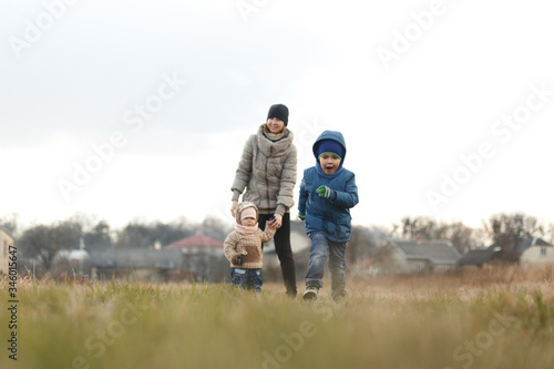 Young mother with two children, a little girl and a boy playing in the autumn field.