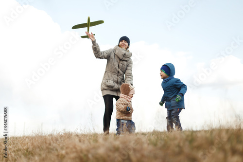 Wallpaper Mural Young mother with two children, a little girl and a boy playing in the autumn field. Autumn family in the Park playing with toy airplane. Torontodigital.ca