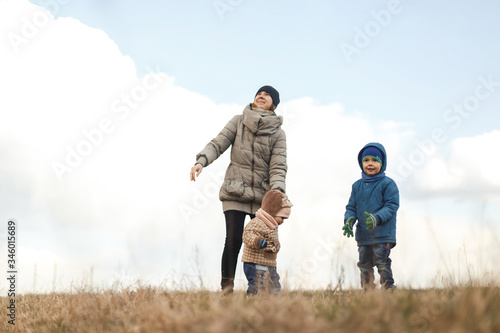 Young mother with two children, a little girl and a boy playing in the autumn field. Autumn family in the Park playing with toy airplane.