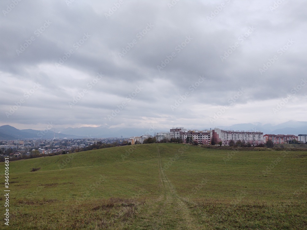 Obraz premium Sunrise and sunset, beautiful clouds over the meadow, hills and buildings in the town. Slovakia