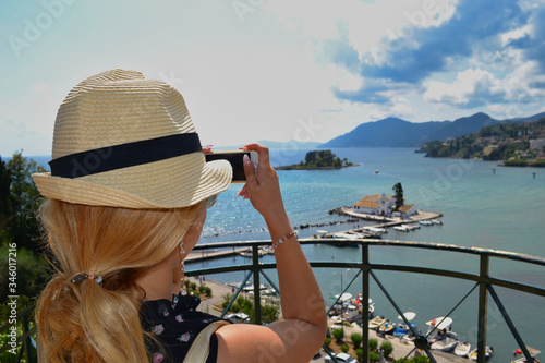 Girl taking a photo of the Vlacherna Monastery view, Kanoni, Corfu, Grecce photo