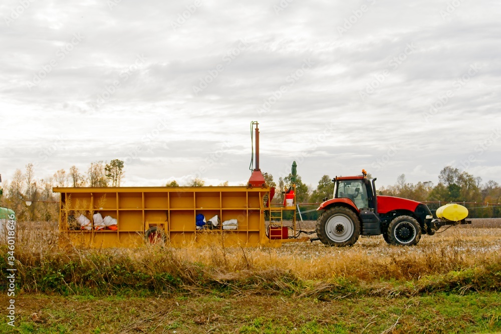Fototapeta premium Farm tractor in field getting ready to load cotton bails for transportation