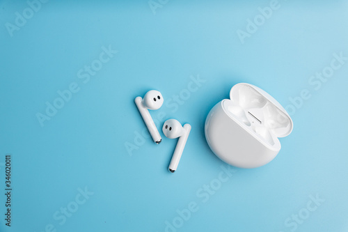 Wireless headphones in white on a blue isolated background.