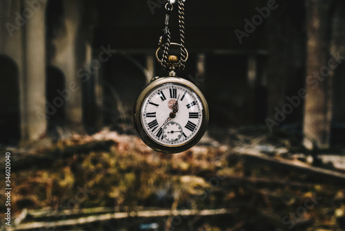 Vintage silver watch with chainlet hanging over the ruins of the cathedral. The wind of time concept. photo