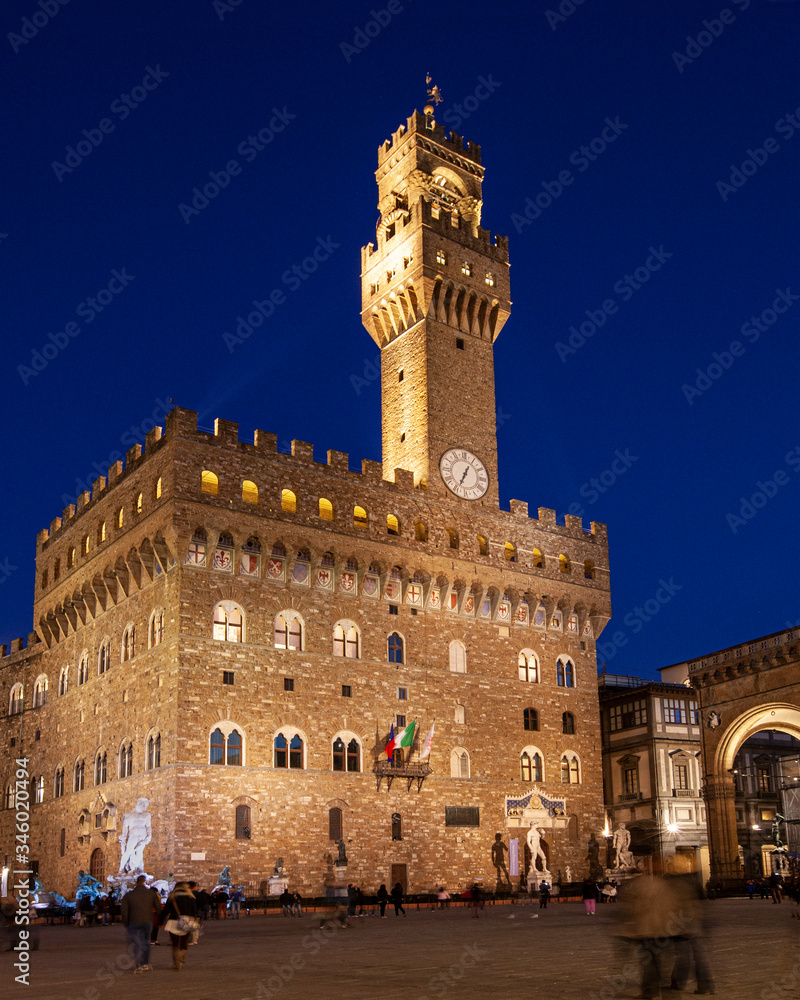 Florence's Palazzo Vecchio, with David statue, lit against beautiful blue evening sky, with part of Piazza della Signoria in foreground.