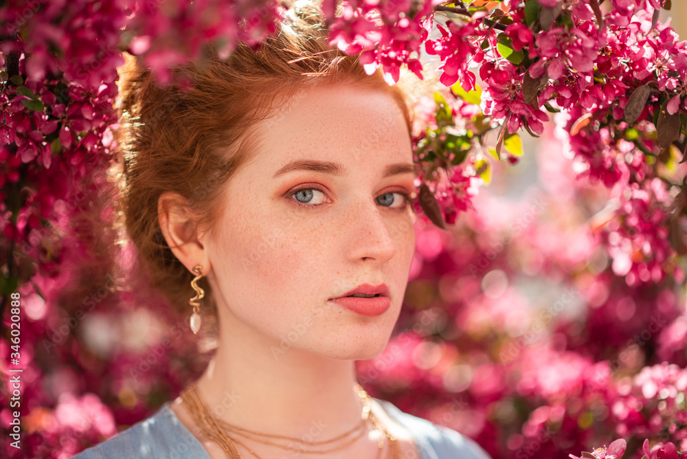 Young beautiful redhead girl with natural freckled skin posing in blooming garden. Outdoor close up portrait. Copy, empty space for text Young beautiful redhead girl with natural freckled skin posing in blooming garden. Outdoor close up portrait. Copy, empty space for text