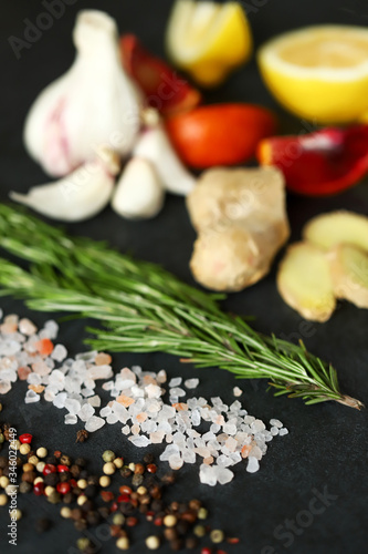 Selective focus. Set spice on a black stone board. Peppers mix, Himalayan salt, rosemary, garlic, lemon, ginger, red orange. Spices for fish or meat. Spices for marinade. Spices for a healthy diet.