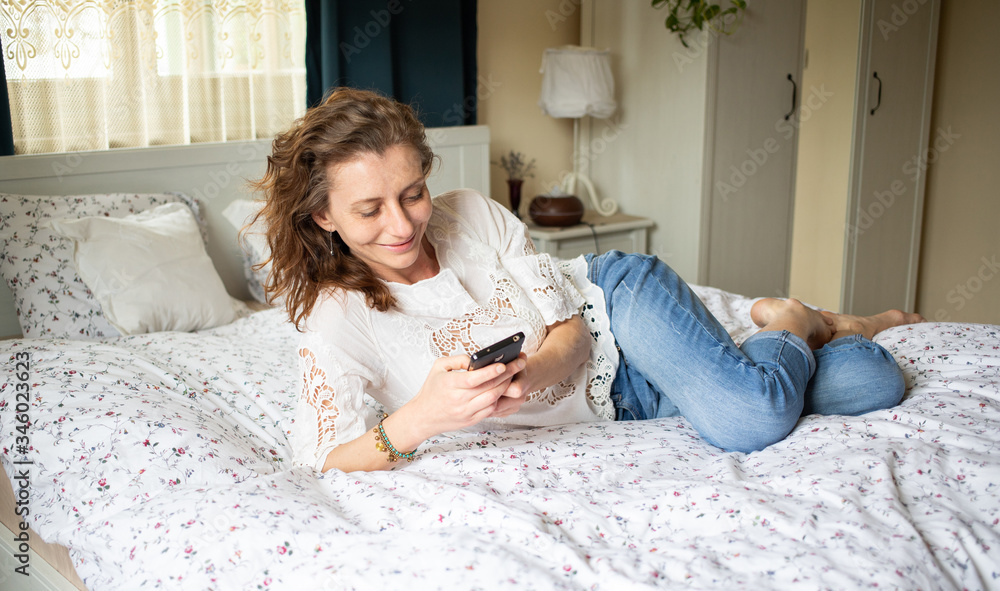 happy relaxed woman using smartphone in bed to connect socially