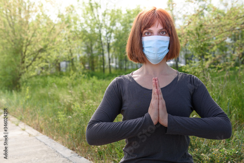 Girl in lotus position with sirurgical mask in nature background. photo