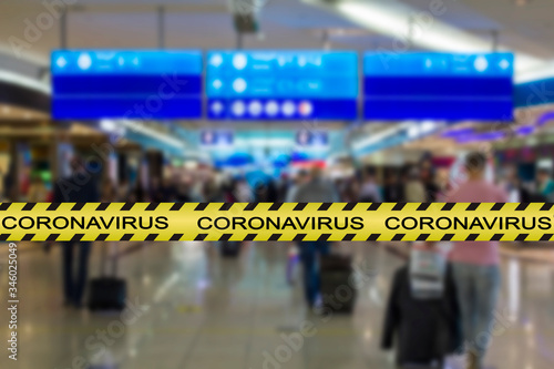 Coronavirus warning tape with blurred airport image on the background. COVID-19 spread and restrictions concept